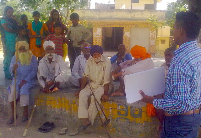 A photo showing a man preaching the gospel to a group of Indian men.